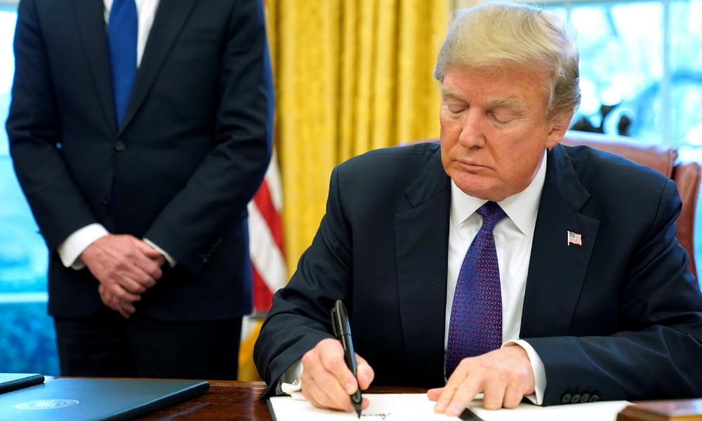 Donald Trump firma con marcadores negros