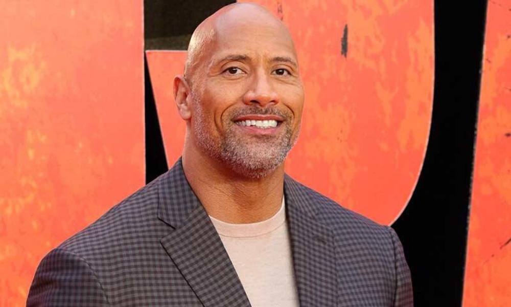 Imagen revelaría que ‘The Rock’ protagonizaría remake de un clásico de los 90 ‘The Rock’ en Last Action Hero Uno de los actores que se ha vuelto una mina de oro para Hollywood ha sido Dwayne Johnson, pues las cintas donde ha aparecido se han vuelto un éxito total en taquilla, no por nada es de los mejores pagados de la historia, tanto así que se ha involucrado en gran número de cintas, pero ¿Estará ‘The Rock’ en ‘Last Action Hero’? Dwayne ‘The Rock’ Johnson inició su Carrera cinematográfica en 2001 con ‘The Mummy Returns’ después de una exitosa carrera en la WWE y poco a poco ha estado escalando en su carrera, actualmente está al frente de la franquicia de ‘Fast And Furious’ y ‘Jumanji’, donde ha encontrado una mancuerna con Kevin Hart, con quien ha protagonizado varias cintas. En un nuevo diseño de Bosslogic vemos a ‘The Rock’ en ‘Last Action Hero’, esta cinta de 1993 protagonizada por Arnold Schwarzenegger, donde es un héroe de acción que sale de la pantalla grnde para evitar que su mayor enemigo domine este mundo. En esta imagen podemos ver también a Kevin Hart, quien se ve como Danny Madigan, quien es interpretado por Austin O’Brien en esta cinta se que volvió en todo un clásico de los 90, justo cuando Schwarzenegger estaba en su mejor momento después de protagonizar la cinta ‘Terminator: Judgment Day’ junto a Linda Hamilton. Actualmente ‘The Rock’ está por estrenar la nueva cinta de ‘Jumanji: The Next Level’, tercera parte de esta franquicia que inició en 1995 con Robin Williams, pero ahora con Karen Gillan, Jack Black, Nick Jonas y por supuesto, Kevin Hart. ¿Será que estará buscando hacer este reboot?